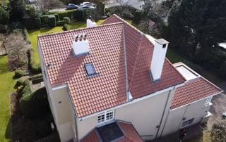 Vue aérienne d’une maison avec toiture inclinée en tuiles rouges réalisée par Belgo-Renov